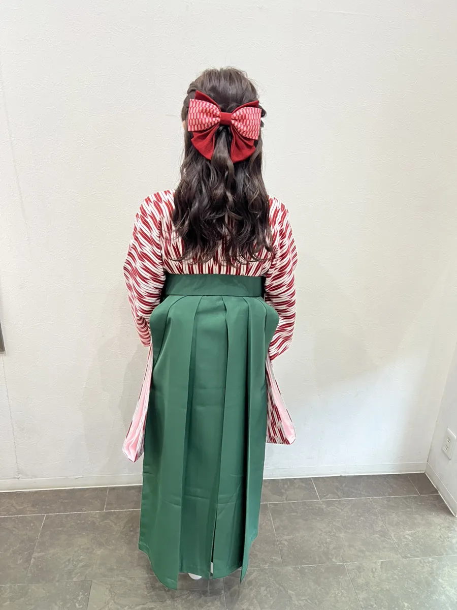 袴の着付けとヘアセットの後ろ姿。矢羽根柄の着物に緑の袴