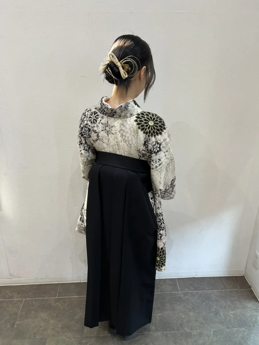 袴の着付けとヘアセットの後ろ姿。白黒の花柄の着物に黒の袴