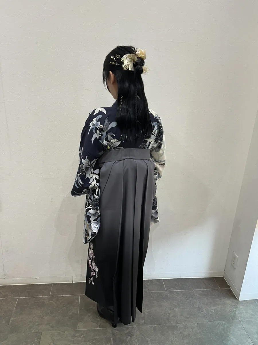 袴の着付けとヘアセットの後ろ姿。紺の花柄の着物にグレーの袴