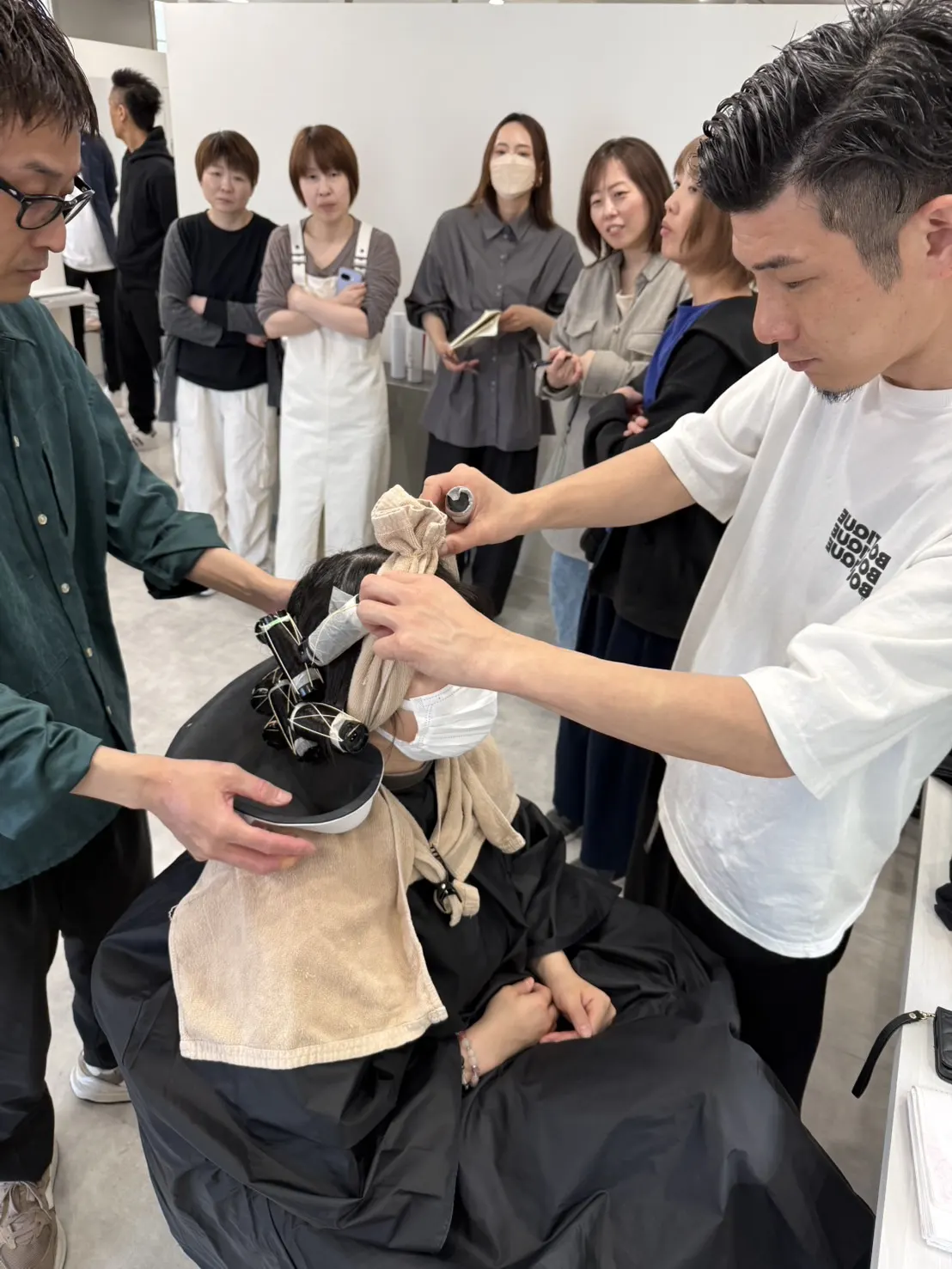 ローラー巻きの実演を間近で確認するスタッフ